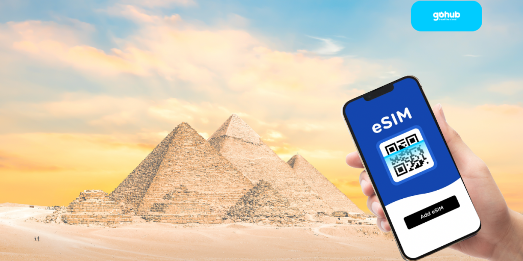 Hand holding phone with eSIM QR code in front of the pyramids in Egypt