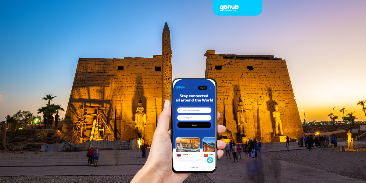 Tourist using GoHub eSIM in front of Luxor Temple at sunset