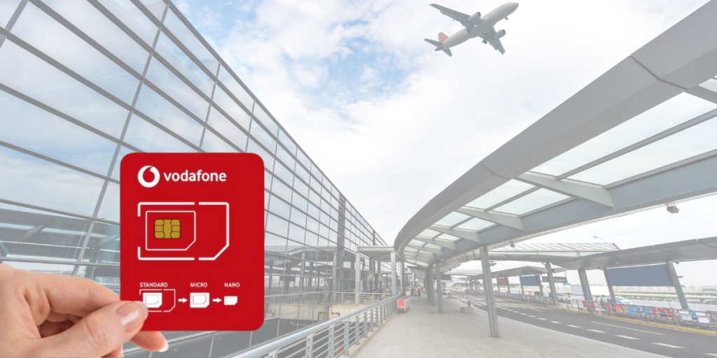 Hand holding Vodafone SIM card in front of Cairo airport