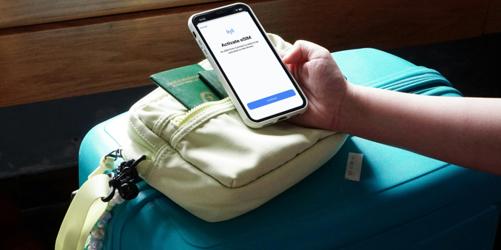 Traveler activating an eSIM on their phone before a trip, with passport and luggage on the table.