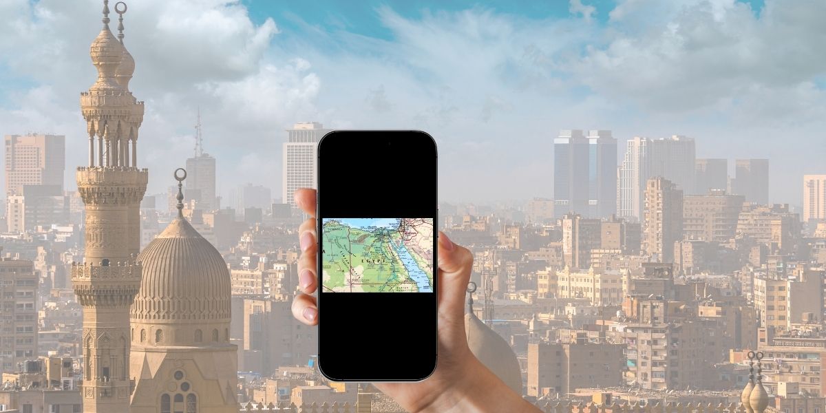 Traveler holding a smartphone showing an Egypt map with Cairo skyline in the background, illustrating the convenience of using eSIM in Egypt